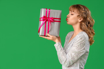 Beautiful young woman with gift box on green background. Valentine's Day celebration
