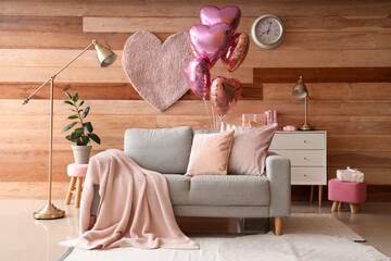 Interior of festive living room with grey sofa and heart-shaped balloons. Valentine's Day celebration