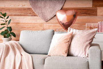 Interior of festive living room with grey sofa and heart-shaped balloons. Valentine's Day...