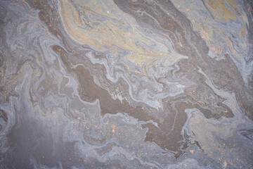 A marble texture of a rainbow spill of gasoline on a sidewalk in a puddle as a background.