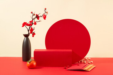 A red podium is displayed with a vase of peach blossoms, tangerines and lucky money envelopes....
