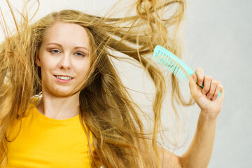 Blonde girl long tangled hair holds comb