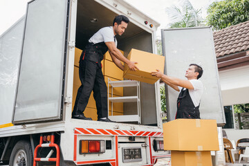 With smiling faces removal company workers efficiently unload boxes and furniture from the truck...