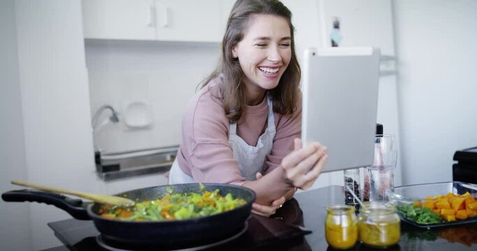 Woman, video call with tablet and cooking in kitchen for lunch or dinner, communication and meal prep for social media. Nutrition, talk while preparing food and virtual chat on blog with technology