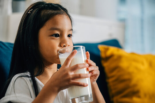 In the comfort of his home an Asian boy relishes a glass of milk on the sofa showcasing happiness and innocence. This image beautifully represents the concept of healthy food and drink for children.