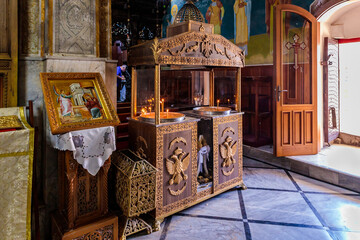 Large icon on the stand and place for lighting candles in the main hall of the Greek Orthodox...