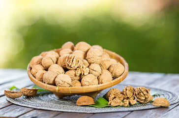 Walnuts in wooden tral on green bokeh background, Walnuts kernels on wooden table.
