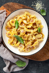 Traditional italian food. Dish with ravioli, tomato, Sun-dried tomatoes, basics and grated cheese. Tasty pasta