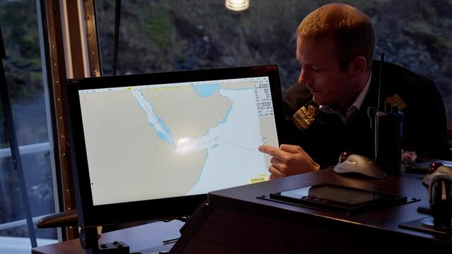 Captain showing voyage through Red Sea and Yemen on electronic map, worried
