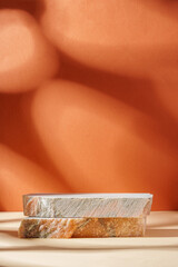 Piece of granite stone against beige background with shadows