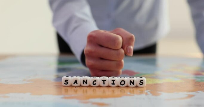 Hand knocking on table with fist on world map near word sanctions closeup 4k movie slow motion