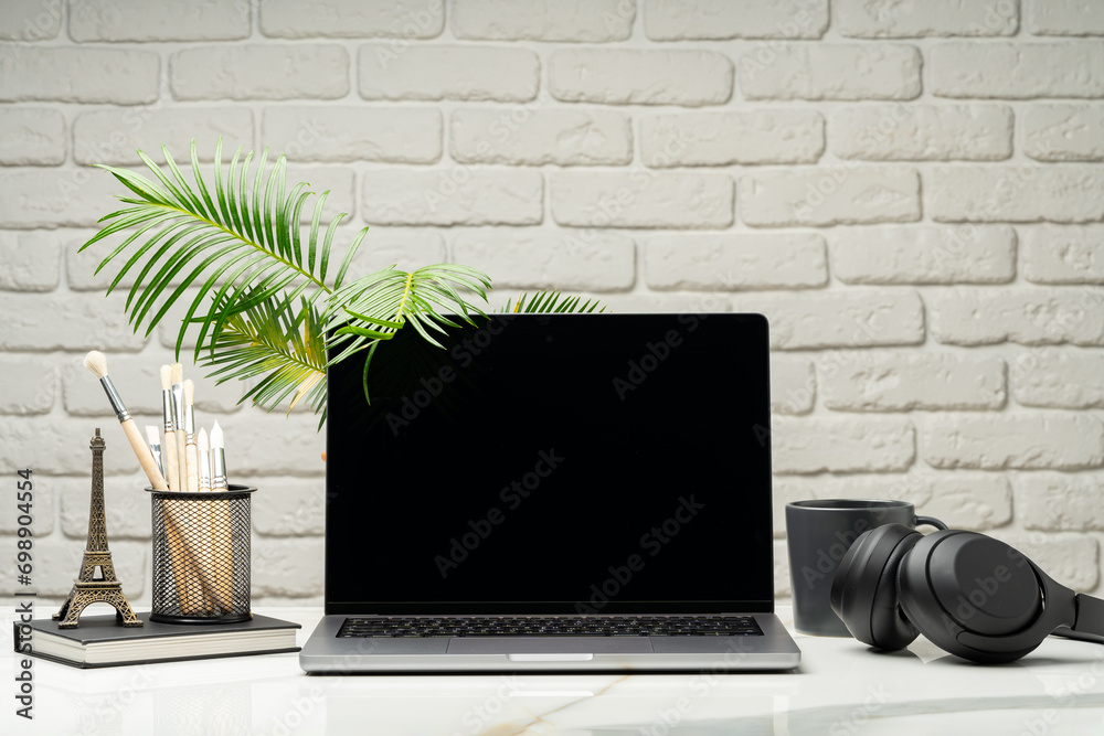 Sticker Laptop with black screen on desk against white brick wall