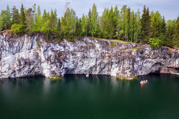 Karelian landscape photo. Tourists in boat sailing the former marble quarry