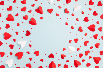 Valentine day minimalist festive pattern background from mixed red hearts on pastel blue table top...