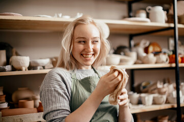 A smiling female potter in the workshop against a rack of pottery. Taking a break from moulding...