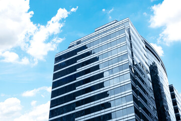 Bottom up view modern office building with glass window on blue sky background