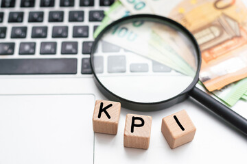 Magnifying glass over text KPI on wooden cube blocks on white office table. key performance indicator