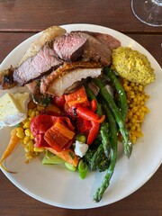Buffet BBQ lunch combination of meat, vegetables and cheese on the white plate