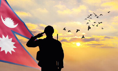 Silhouette of a soldier with the Nepal flag stands against the background of a sunset or sunrise....