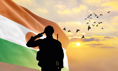 Silhouette of a soldier with the Niger flag stands against the background of a sunset or sunrise. Concept of national holidays. Commemoration Day. - obrazy, fototapety, plakaty