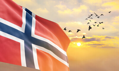 Waving flag of Norway against the background of a sunset or sunrise. Norway flag for Independence Day. The symbol of the state on wavy fabric. - obrazy, fototapety, plakaty