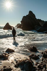 Man walking on beach near rocks