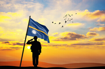 Silhouette of a soldier with the Nauru flag stands against the background of a sunset or sunrise. Concept of national holidays. Commemoration Day.