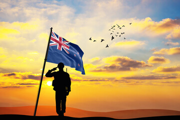Silhouette of a soldier with the New Zealand flag stands against the background of a sunset or...