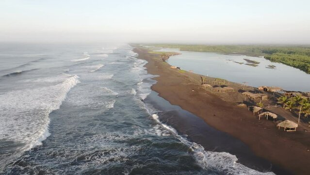 Flying low above black sand beach at El paredon Guatemala during sunrise - Drone shot