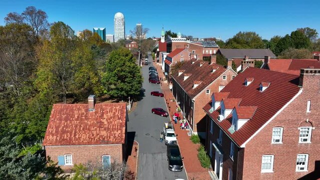 Historic Salem streets with Winston-Salem skyline in distance on autumn day. Aerial.