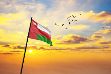 Waving flag of Oman against the background of a sunset or sunrise. Oman flag for Independence Day. The symbol of the state on wavy fabric.