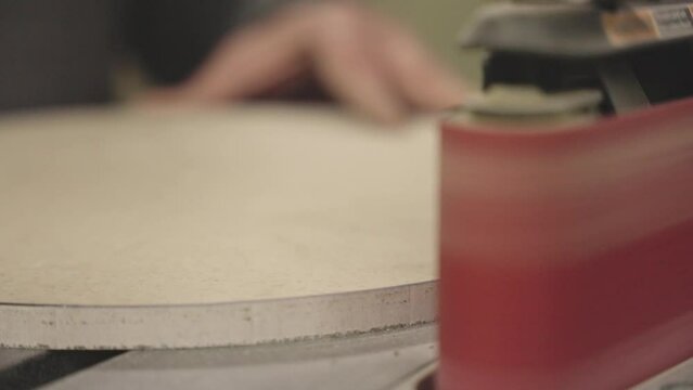 close up of a person sanding wood on a machine