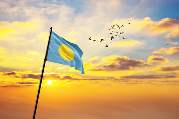 Waving flag of Palau against the background of a sunset or sunrise. Palau flag for Independence Day. The symbol of the state on wavy fabric.
