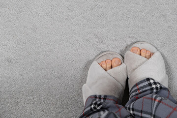Stylish Modern Fluffy Grey House Slippers on Women's Feet on Carpet, Top View, Place for Text
