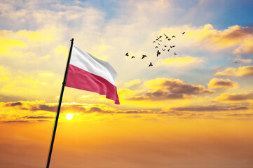Waving flag of Poland against the background of a sunset or sunrise. Poland flag for Independence Day. The symbol of the state on wavy fabric.