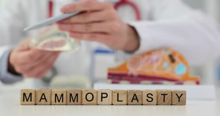 Word mammoplasty written on cubes near doctor with breast implant 4k movie slow motion