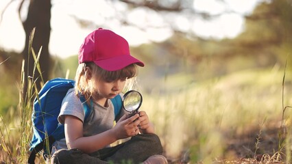 child girl boy scout studying a pine cone in the forest with a magnifying glass. happy family child...