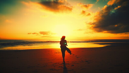 Fototapeta na wymiar Silhouette of a sexy slender woman running along the waves towards the sun at an orange sunset near the seashore, walking along the warm ocean water at an orange summer sunset. Slow motion in 4K