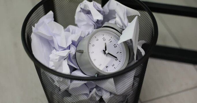 Alarm clock throwing into trash bin with crumpled documents closeup 4k movie slow motion
