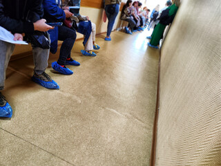 Obraz premium People are sitting in the hallway at the hospital waiting for a visit to the doctor. Legs in line. Crowd