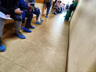 People are sitting in the hallway at the hospital waiting for a visit to the doctor. Legs in line....