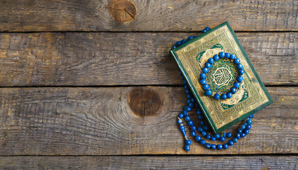 Quran and beads on wooden table.