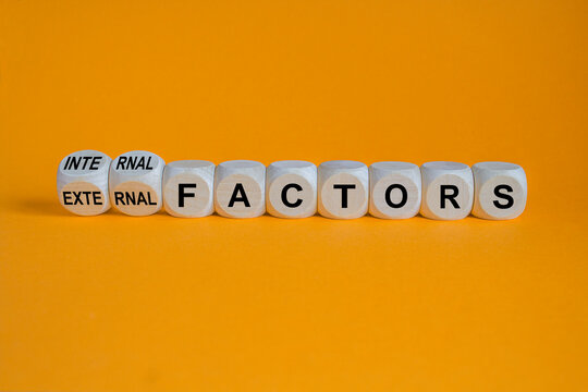 External or internal factors symbol. Turned cubes, changes words external factors to internal factors. Beautiful orange background, copy space. Business, internal or external factors concept.