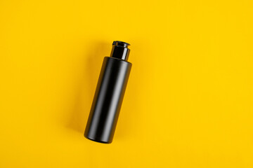Black cosmetic flip top bottle isolated on yollow background.