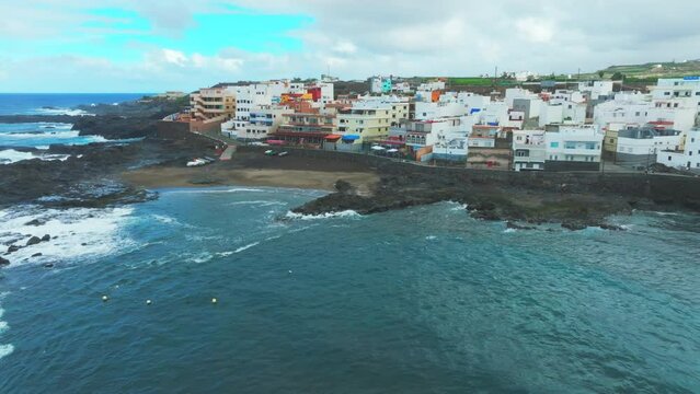 Cinematic and orbital aerial view over the beach and coast of El Puertillo in the north of the island of Gran Canaria and with large waves hitting the coast.