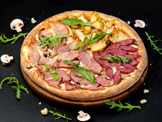 Pizza with cheese, ham and arugula on a black background. Delicious pizza with meat and cheese