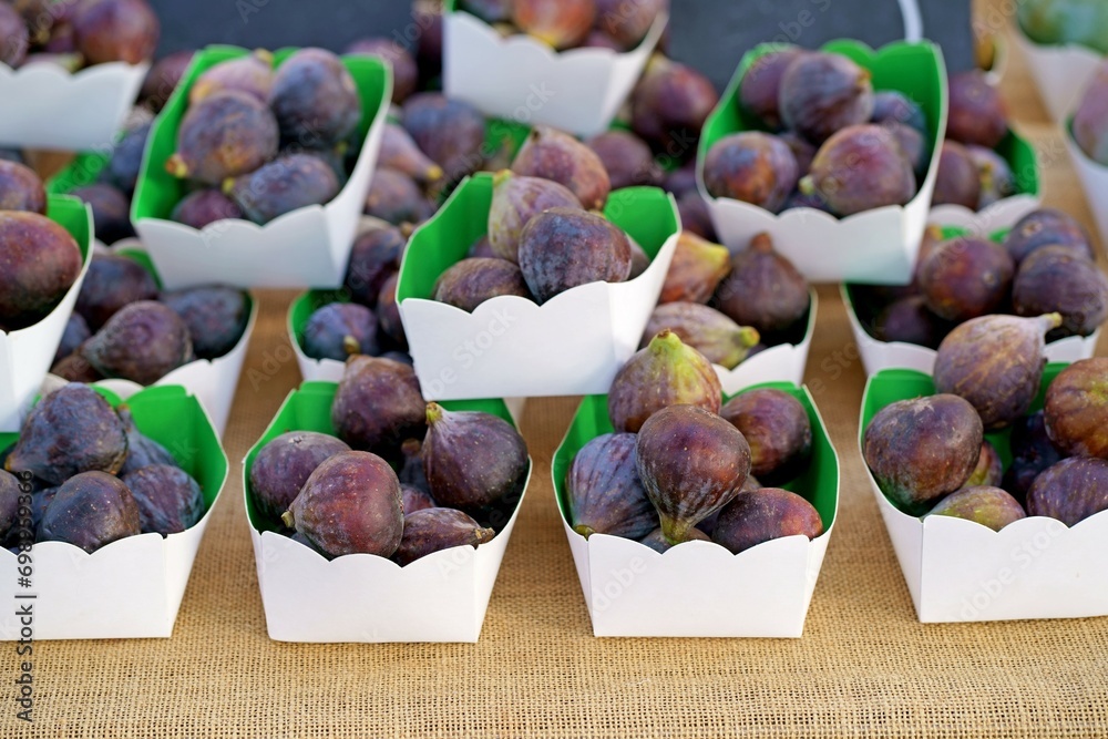 Sticker Fresh figs in a paper box. Fresh organic figs being sold on the table at a farmers market