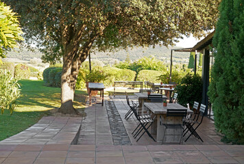 Obraz premium Spain. Summer area of a beautiful restaurant. Spanish cafe tables. Lots of empty tables, chairs on cozy seating area with green mountains. Garden furniture