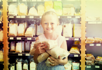 Girl posing with packs of rice in supermarket