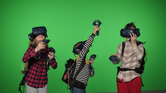 Teenage children use VR headset helmets to play an imitation game on a green background. Viewing 3d 360 virtual reality videos. Children in a virtual reality headset looking around. Chroma key. 